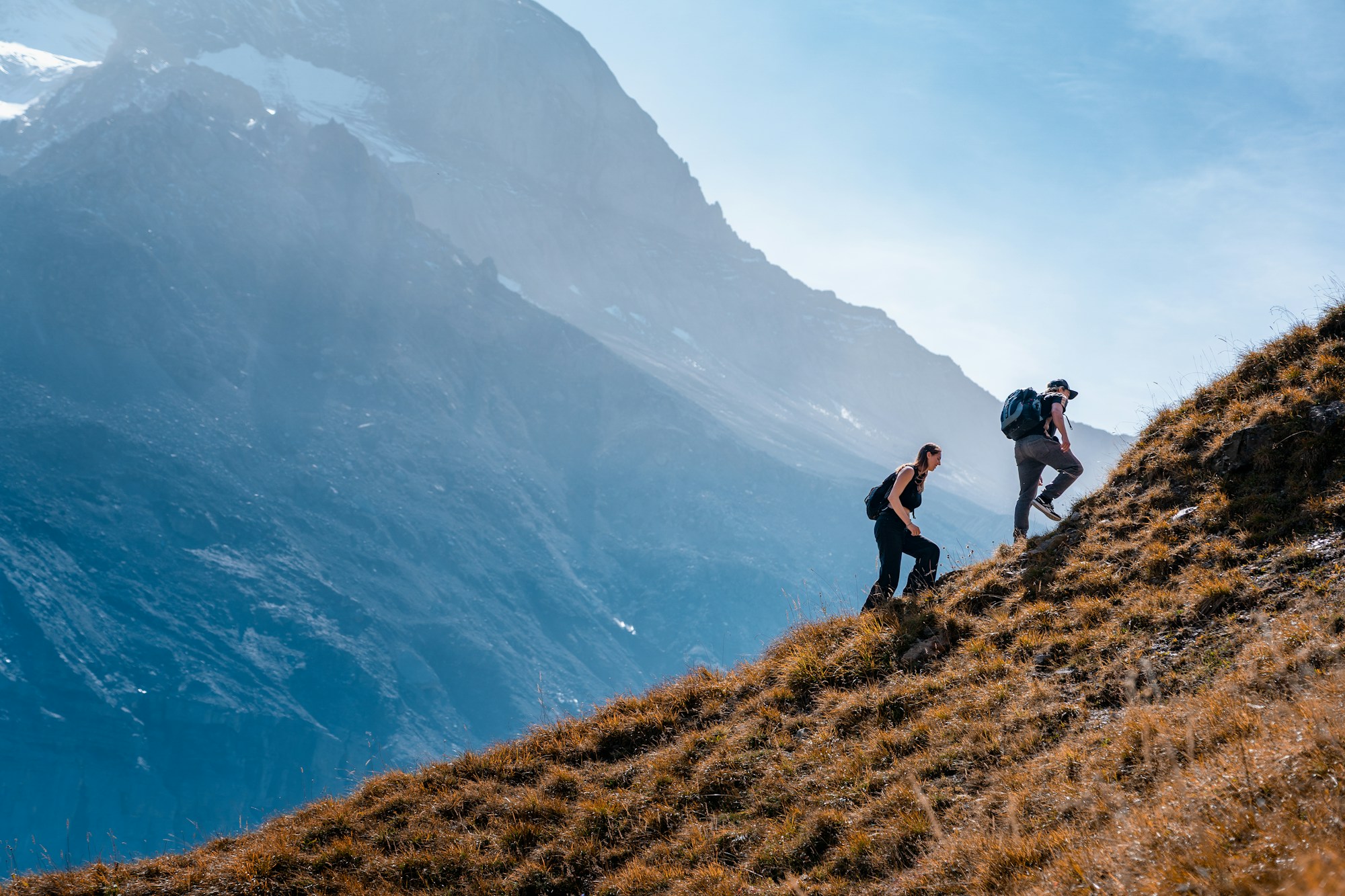 Two hikers climbing a steep mountain slope together