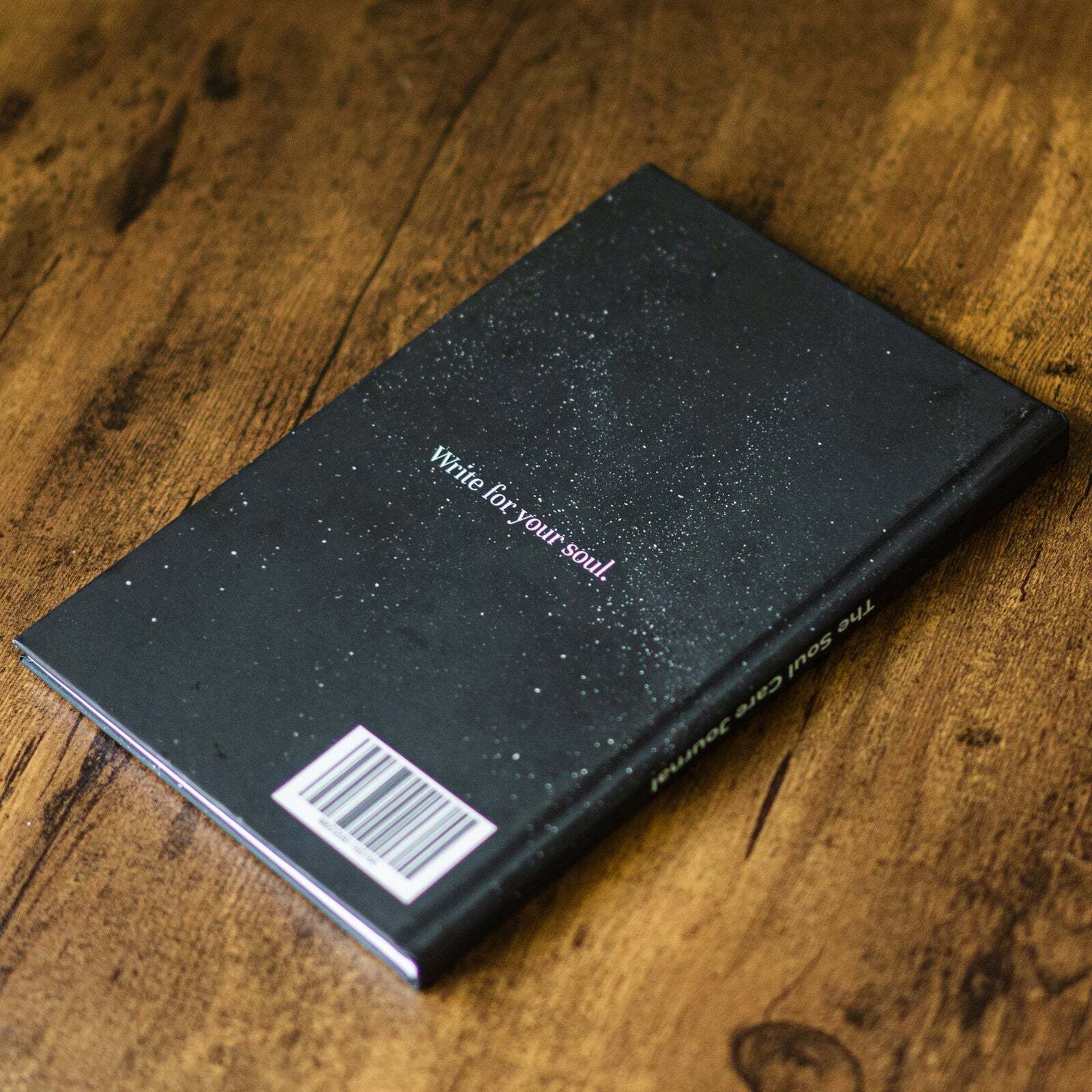 The back cover of the Soul Care Journal reading "Write for your soul" on a wooden table